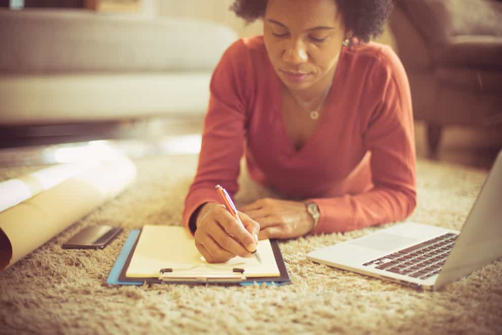 Woman lying on the floor writing a to-do list