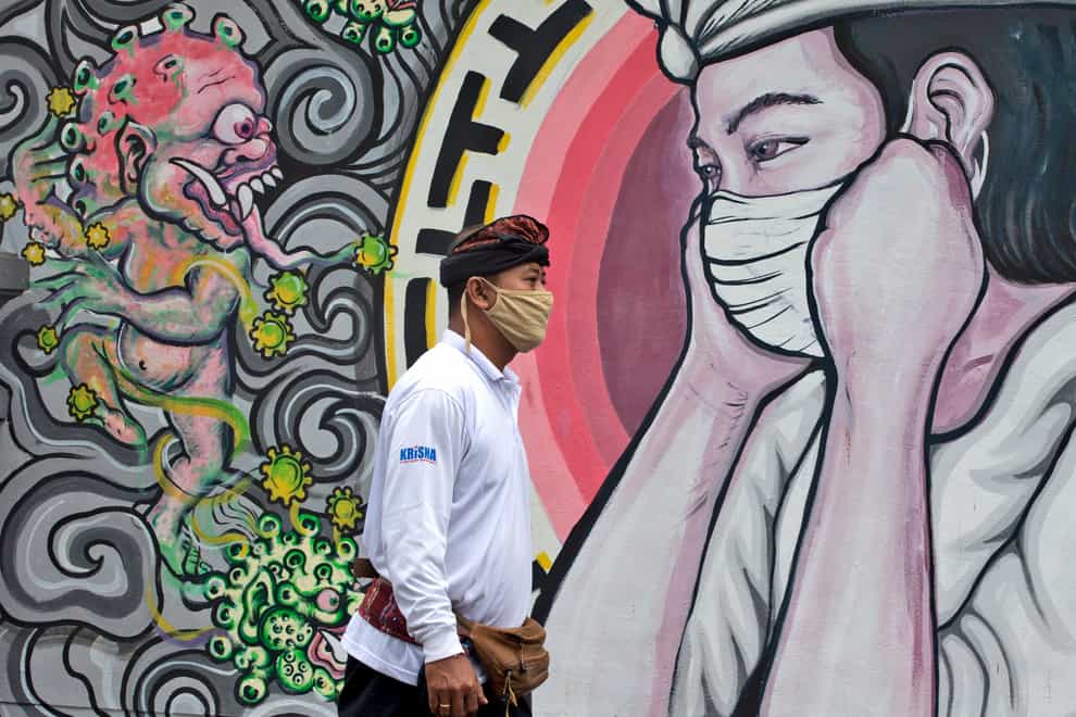 A man walks past a coronavirus-themed mural in Bali, Indonesia