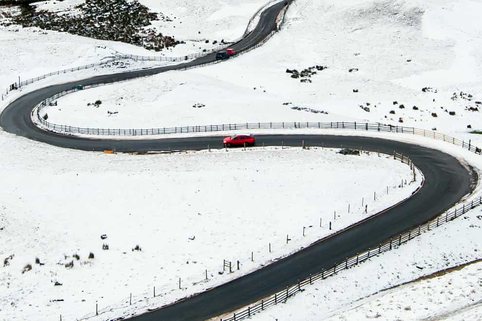 A car navigates a snow-covered scene in the Peak District
