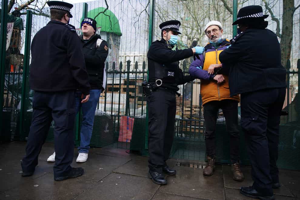 Police officers detain a man at the encampment in Euston Square Gardens