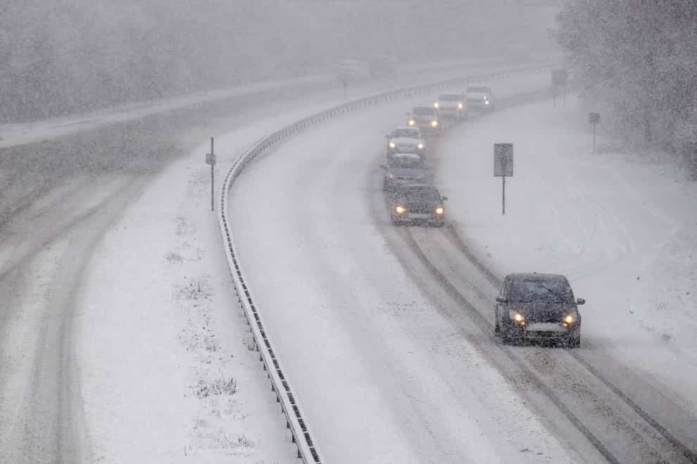 Cars drive through snow on motorway