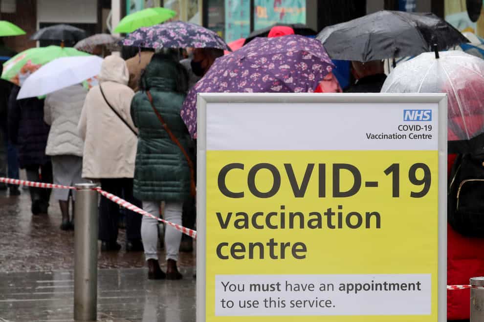 People queue in bad weather to enter a Covid-19 vaccination centre in Folkestone, Kent