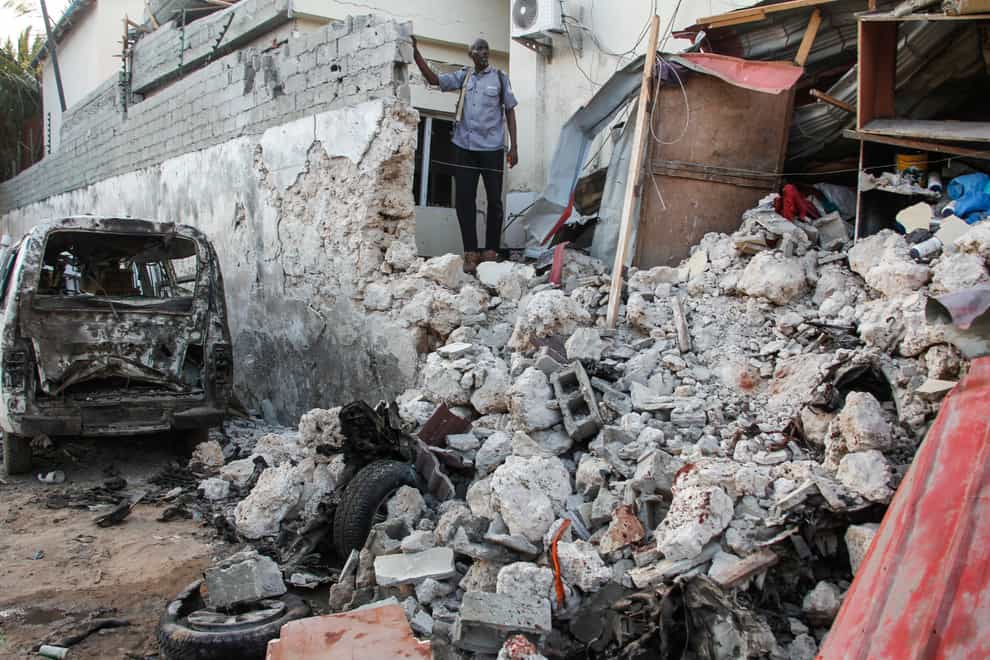 A hotel security guard stands by wreckage in the aftermath of an attack on the Afrik hotel in Mogadishu, Somalia (Farah Abdi Warsameh/AP)