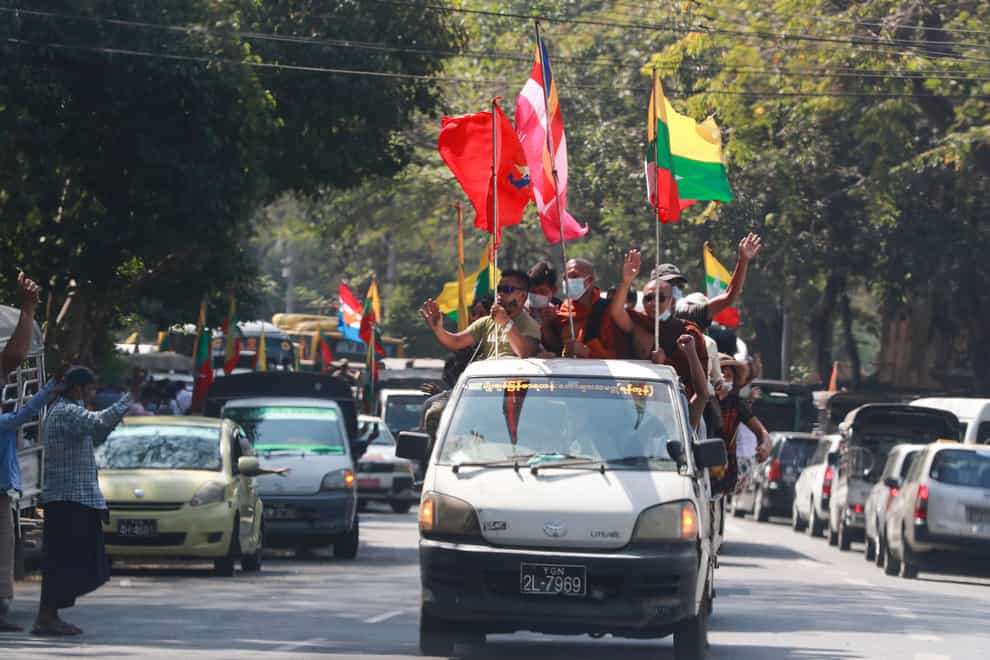 Buddhist religious and military flags are waved by supporters including Buddhist monks onboard a vehicle in Rangoon (Thein Zaw/AP)