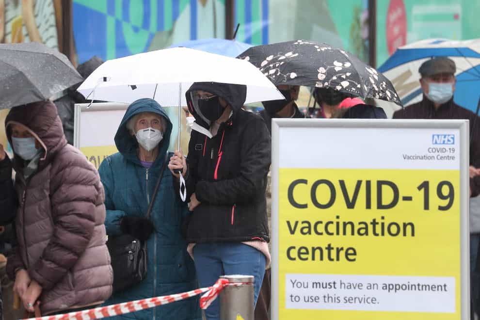 People queue in bad weather to enter a Covid-19 vaccination centre in Folkestone, Kent (Gareth Fuller/PA)