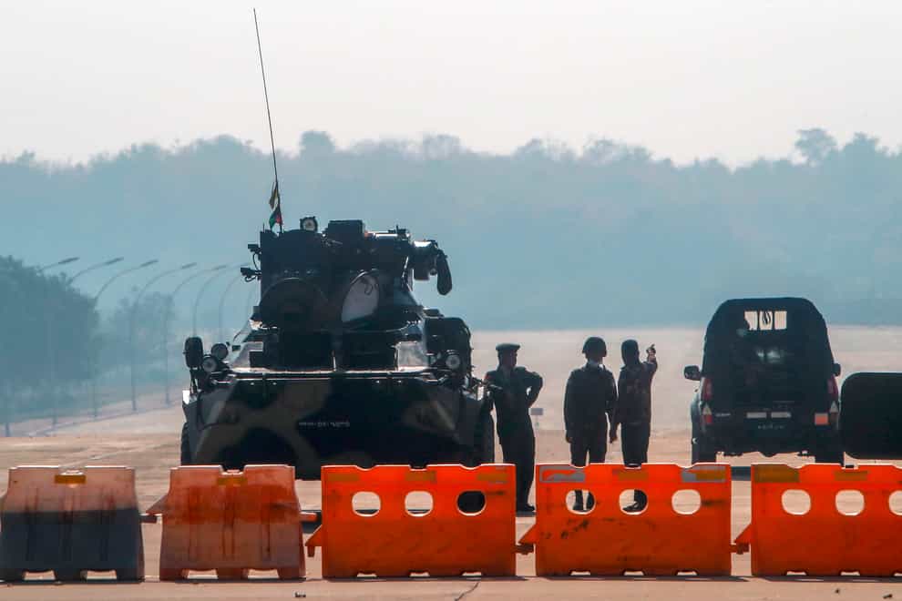 Myanmar’s military stand guard at a checkpoint manned with an armored vehicle in a road leading to the parliament building on Tuesday in Naypyitaw