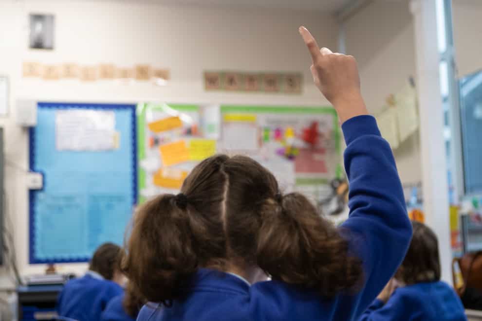 A pupil puts her hand up in class