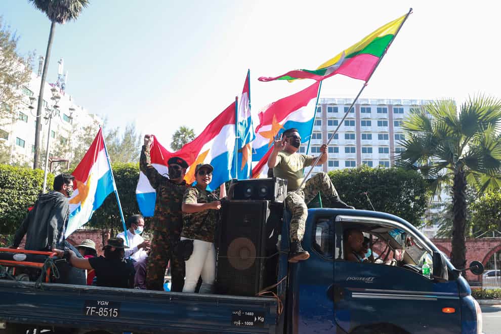 Supporters on a car wave national and military flags in Yangon
