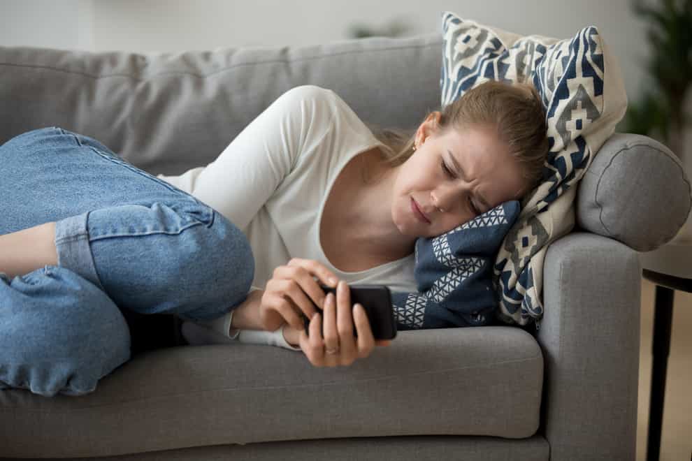 Sad woman with phone on sofa