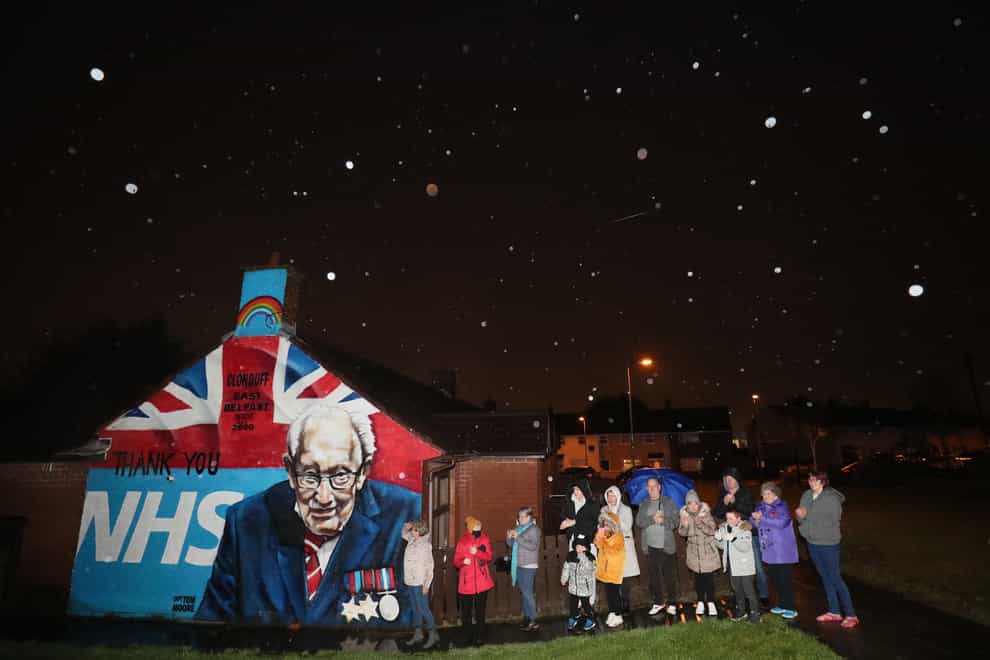 Local residents stand beside a mural of Captain Sir Tom Moore in Clonduff, east Belfast, as they join in with a nationwide clap (Brian Lawless/PA)