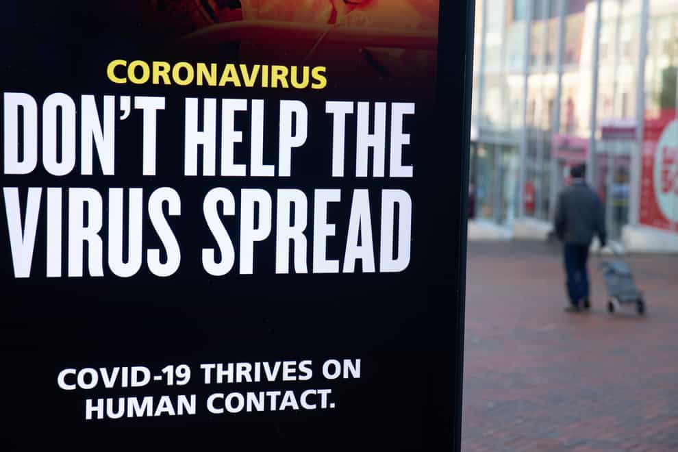 A person passes a ‘Don’t help the virus spread’ government coronavirus sign in Bournemouth