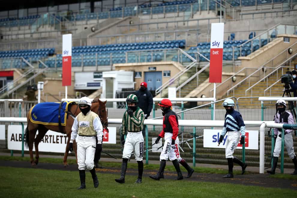 Jockeys wearing facemasks at Doncaster with empty stands behind them - horse racing in Covid times