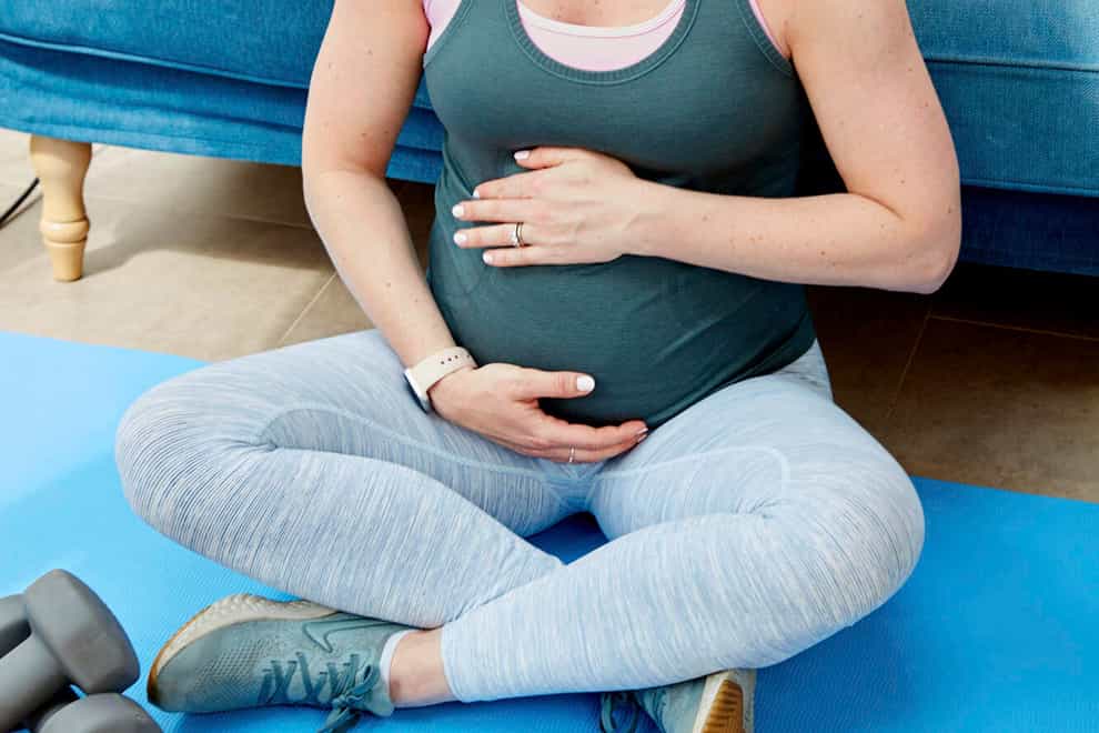 A pregnant woman sitting beside hand weights