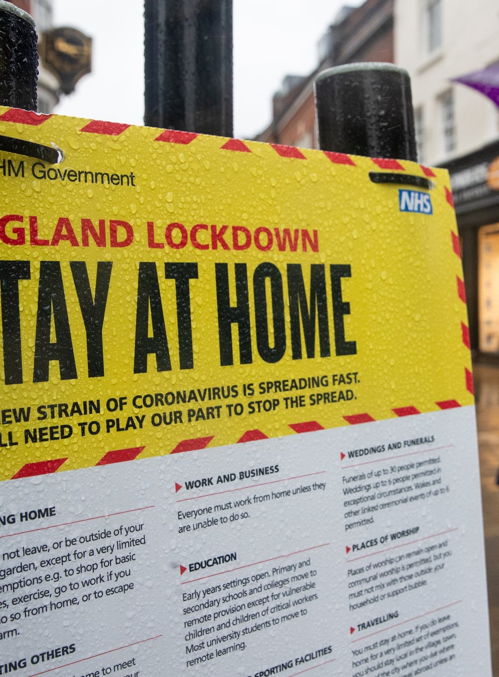 People walk past a Government sign warning people to stay at home