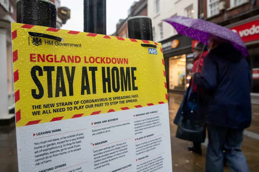 People walk past a Government sign warning people to stay at home