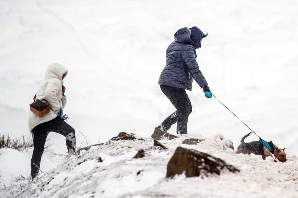 People walk a dog near the Snake Pass in the Peak District, with heavy snow set to bring disruption to south-east England and East Anglia as bitterly cold winds grip much of the nation (Danny Lawson/PA)