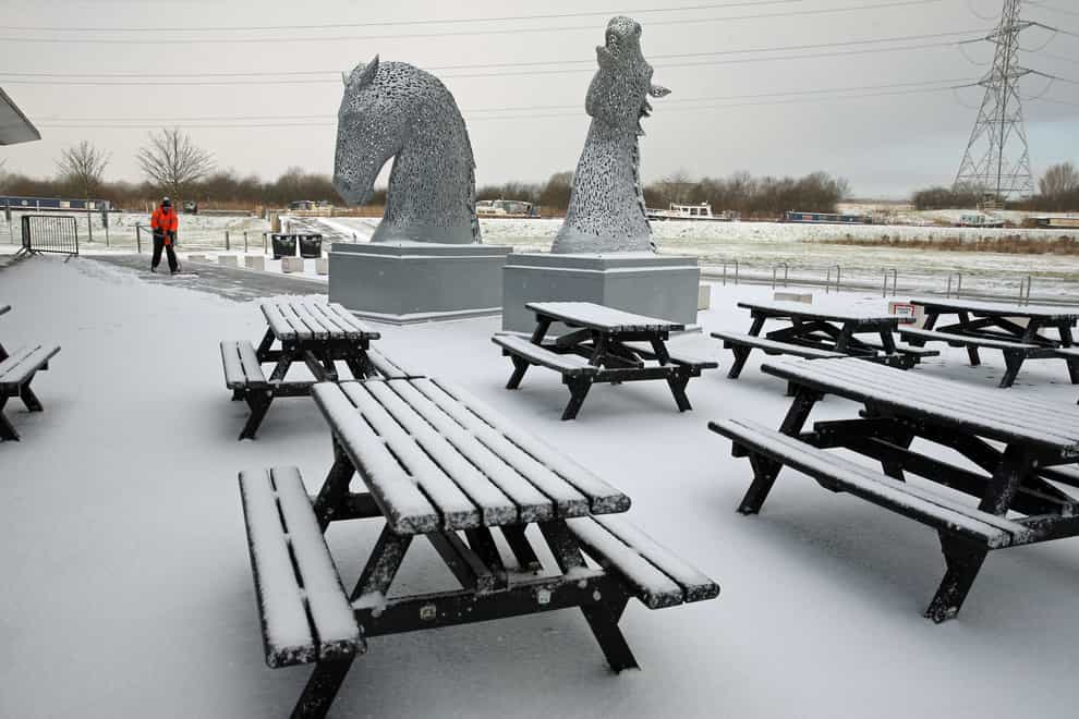 A staff member clears snow on a pathway at the Kelpies, near Falkirk in Scotland