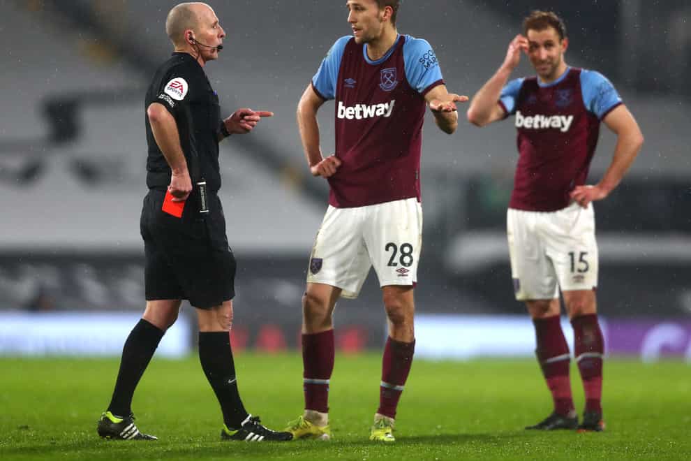 Referee Mike Dean shows a red card to West Ham midfielder Tomas Soucek