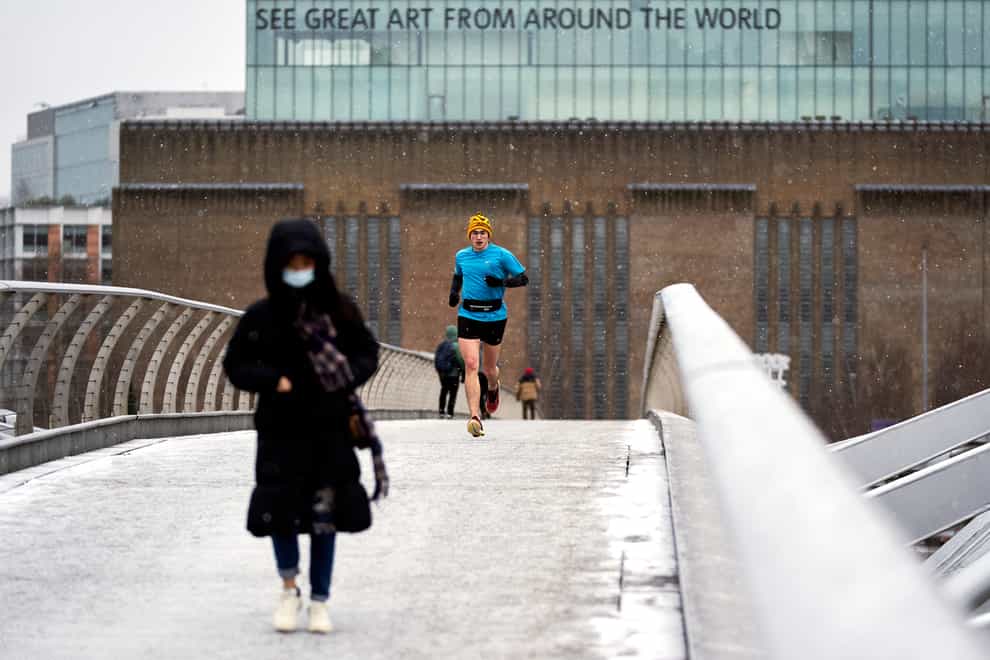 A runner crosses the millennium bridge as snow falls in London on Monday