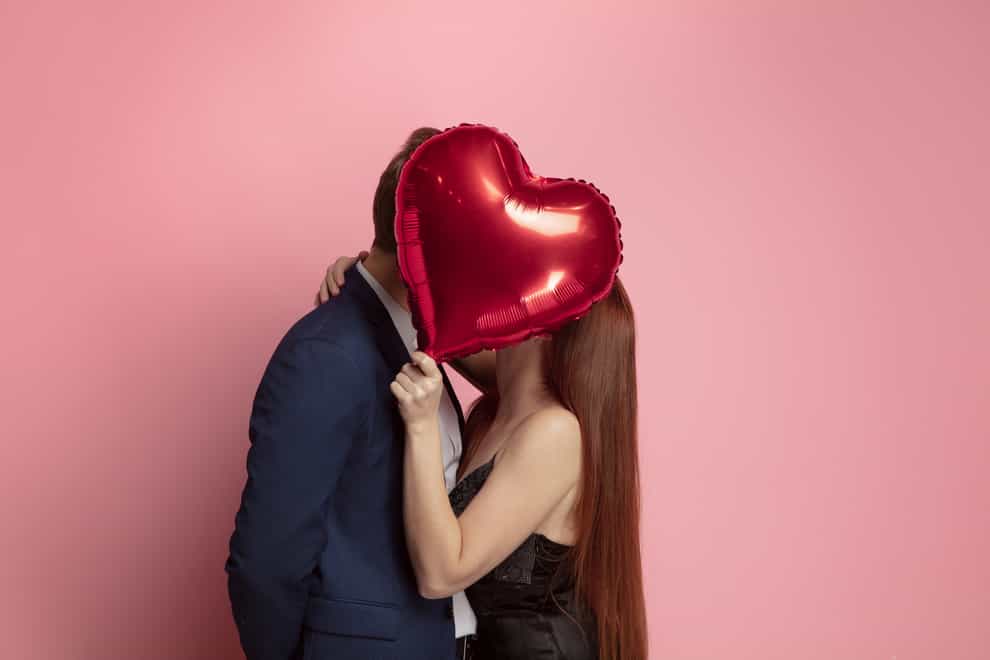 couple kissing behind heart shaped balloon