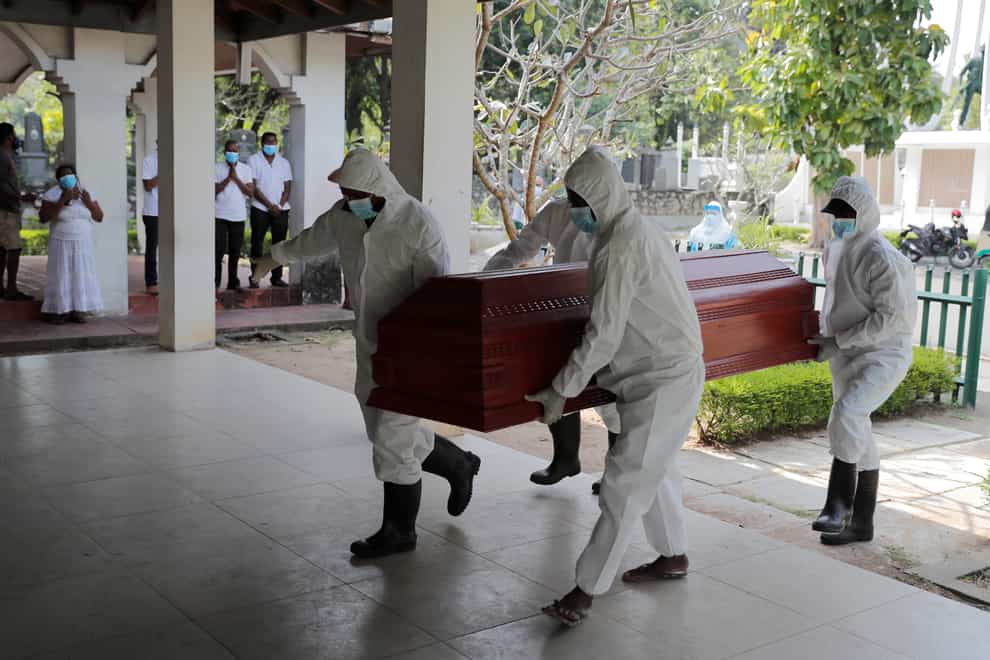 Sri Lankan health workers carry a coffin carrying remains of a Covid-19 victim to a cremation furnace (Eranga Jayawardena/AP)