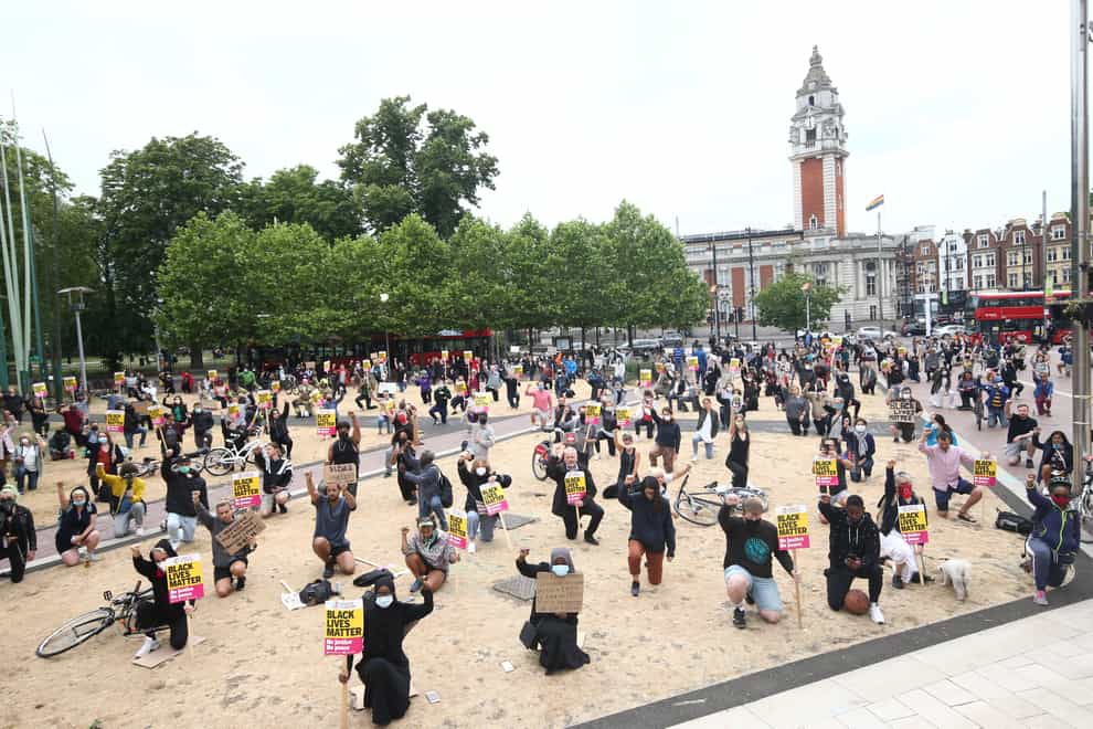 People take a knee during a Black Lives Matter protest rally at Windrush Square, Brixton, south, London, in memory of George Floyd