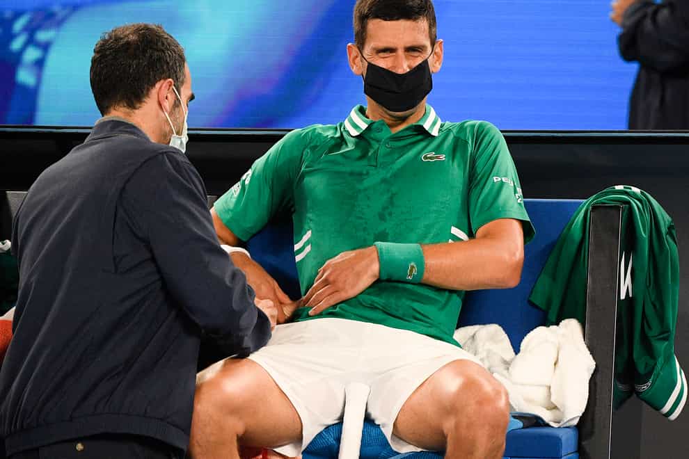 Novak Djokovic receives treatment for a stomach injury