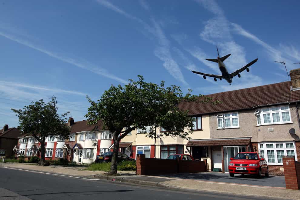 A plane flies over houses