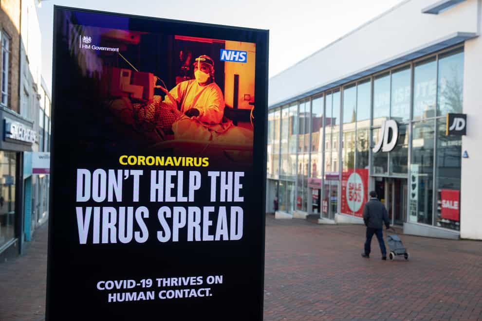 A person passes a ‘Don’t help the virus spread’ government coronavirus warning sign