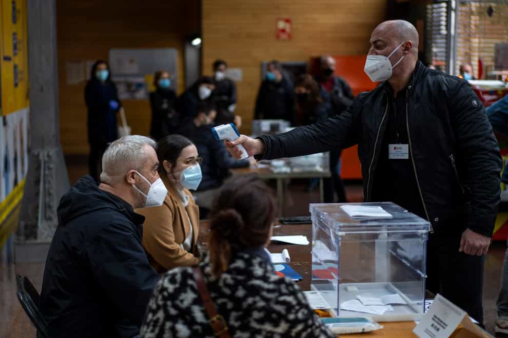 A man working at a polling station has his temperature taken