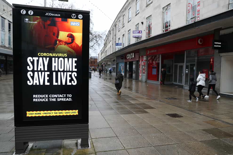 Pedestrians walk past a ‘Stay Home Save Lives’ government sign
