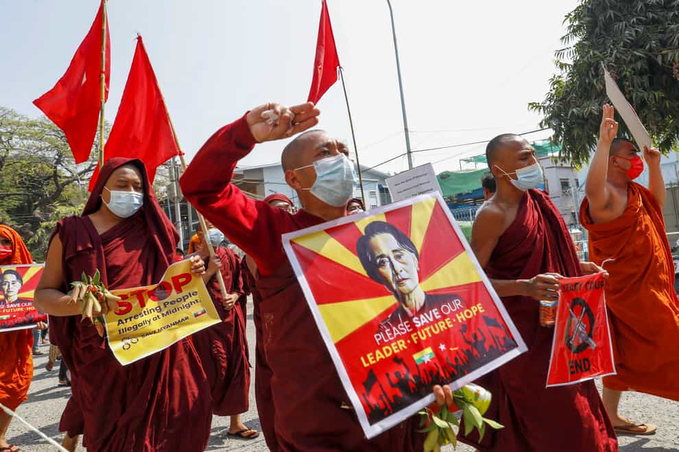 Buddhist monks and nuns display pictures of detained Myanmar leader Aung San Suu Kyi during a protest against the military coup in Mandalay