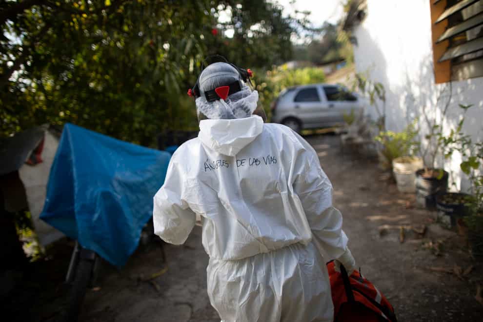 Wearing a biosecurity suit, Dr Debora Mejia, an Angels of the Road volunteer, walks out of a house after visiting two Covid-19 patients in Caracas, Venezuela