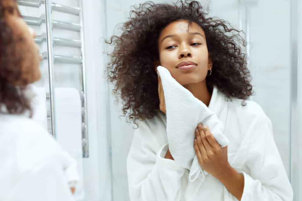 woman drying skin with towel looking in mirror at bathroom