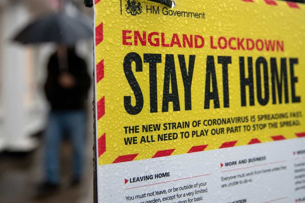 People walk past a Government sign warning people to stay at home (Andrew Matthews/PA)