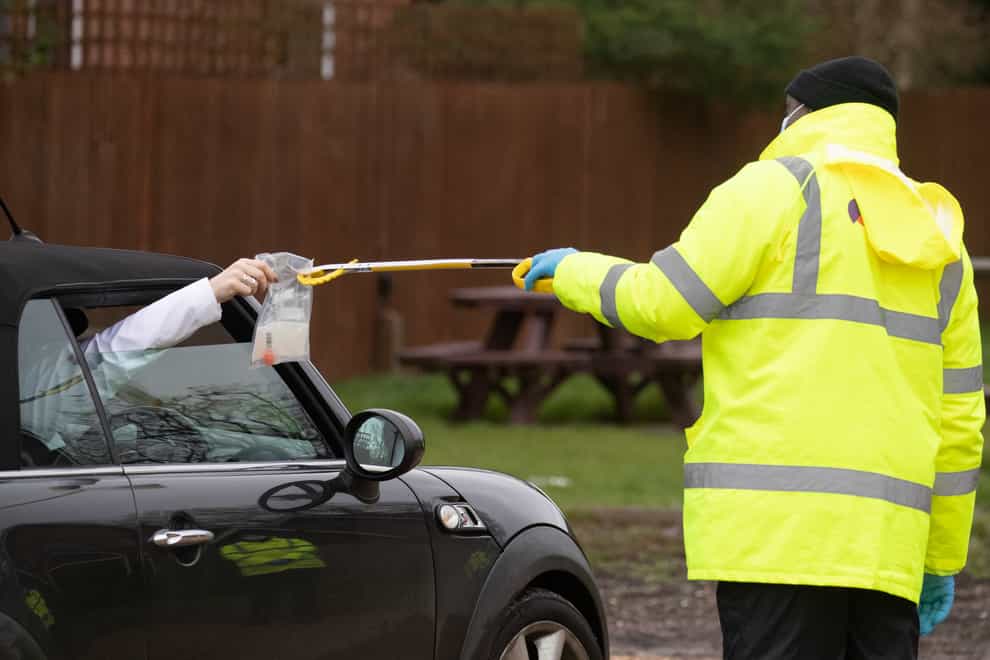 A coronavirus test is handed out of a car window in the car park of the Bramley Inn, Hampshire