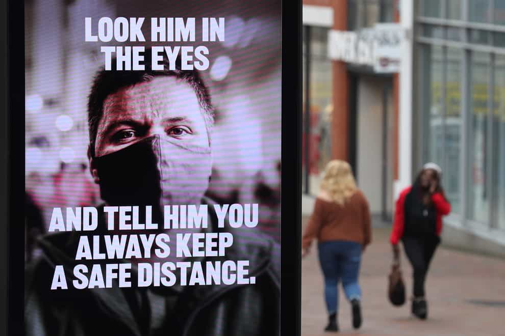 People make their way past a government coronavirus sign on Commercial road in Bournemouth, Dorset, during England’s third national lockdown to curb the spread of coronavirus (Andrew Matthews/PA)