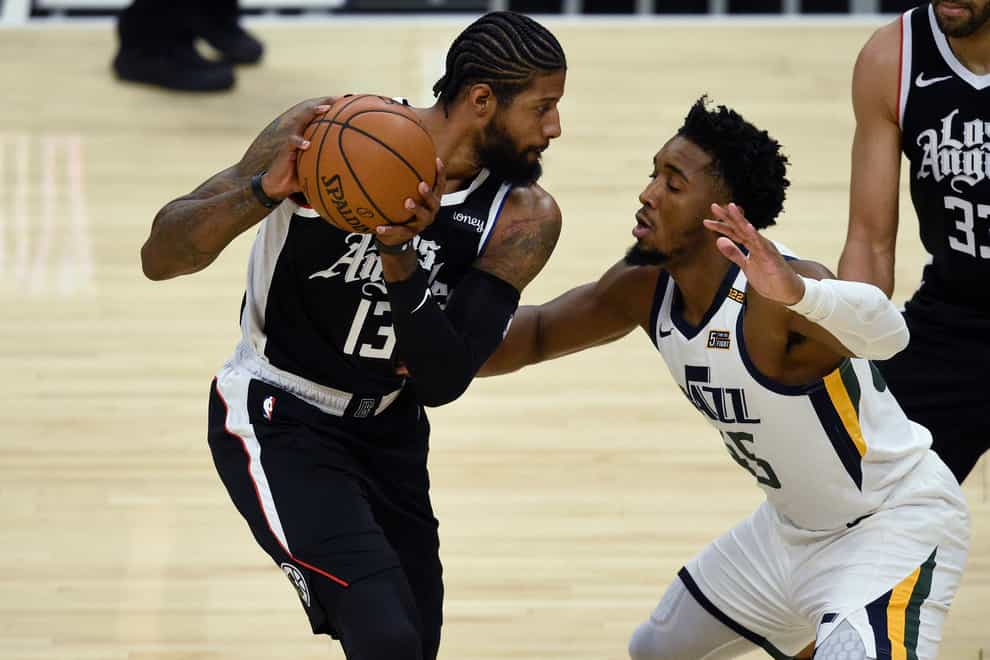 Los Angeles Clippers guard Paul George, left, holds on to the ball while Utah Jazz guard Donovan Mitchell defends