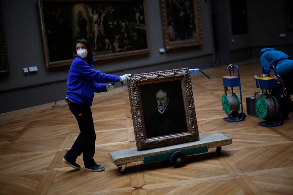 A worker transports the painting called Portrait of Antonio de Covarrubias y Leiva by Spanish painter El Greco in the Louvre museum in Paris