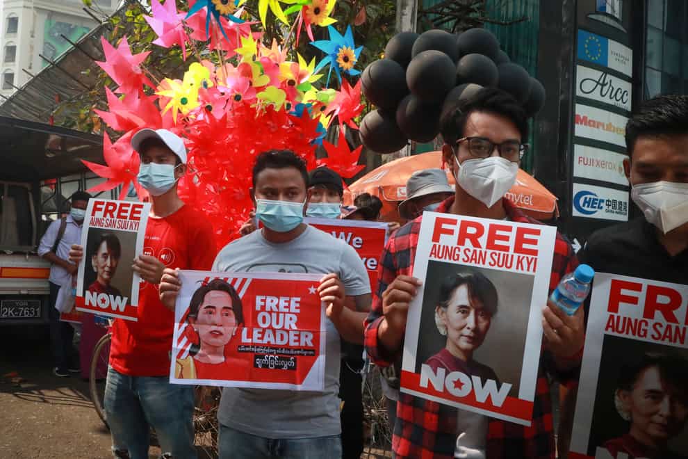 Protesters hold placards and display images of ousted leader Aung San Suu Kyi during an anti-coup protest outside the Hledan Centre in Yangon, Myanmar