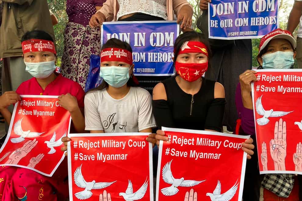Anti-coup protesters hold posters that read “#Reject Military Coup #Save Myanmar” as they gather in Yangon on Monday