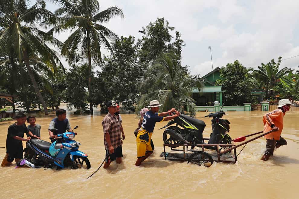 People push belongings through a flooded area in Indonesia