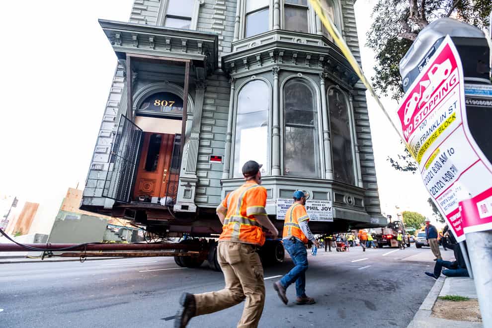 A Victorian house is moved through the streets
