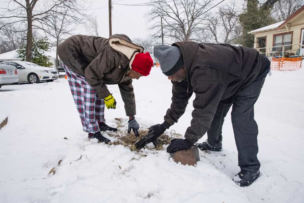 Patricia Broadway, left, and Leon Morris put the cover back after shutting the water off in Ms Broadway’s home in the East Dallas area