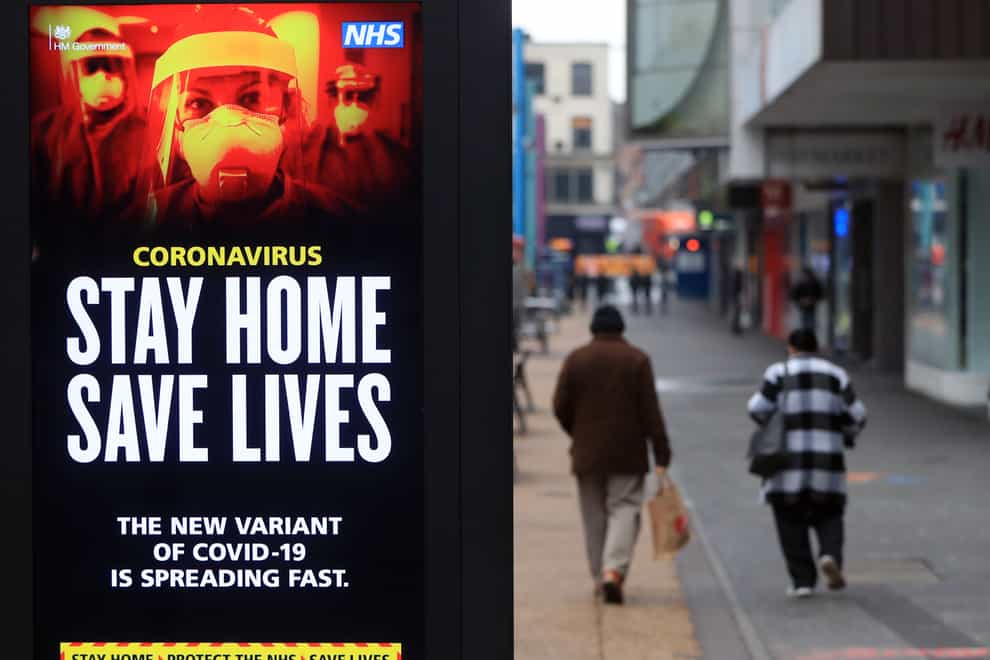 People pass a Stay Home, Save Lives electronic board in Leicester