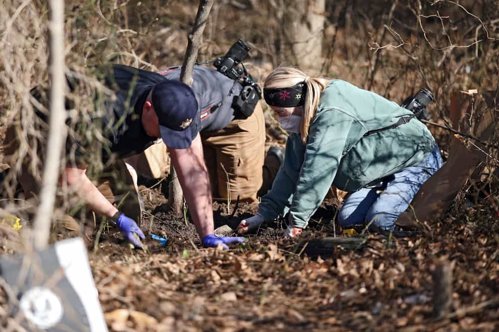 Investigators search through dirt at the scene where skeletal remains were found (Mike Simons/AP)