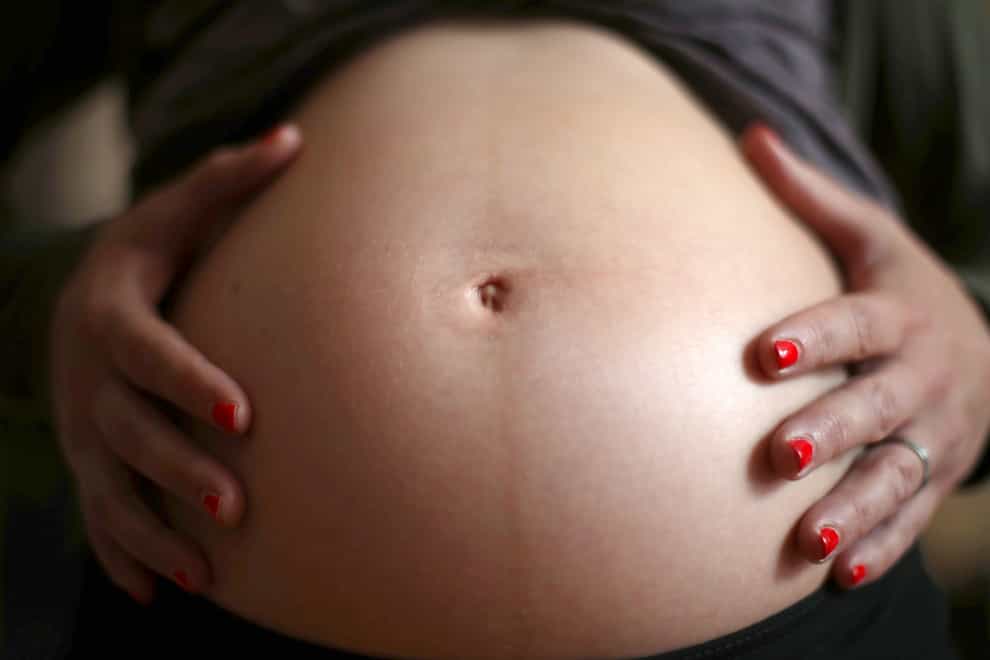 A pregnant woman handles her bump