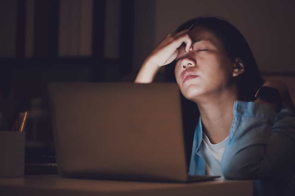exhausted woman in front of a laptop at night