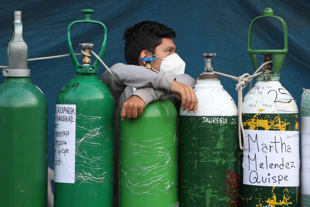 A youth rests on his empty oxygen cylinder waiting for a refill shop to open in Lima, Peru