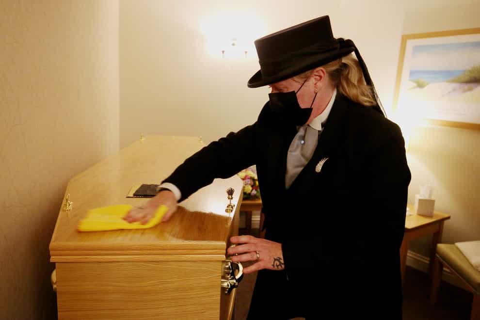 Funeral director Colette Sworn polishes the lid of a coffin as part of her preparations to oversee a funeral in the chapel at Co-op Funeralcare in Watford, Hertfordshire